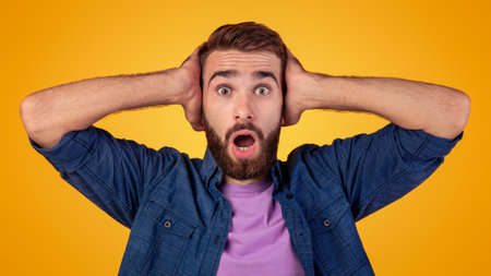 Surprised Caucasian man opening mouth in amazement, looking shocked and stunned on orange studio...