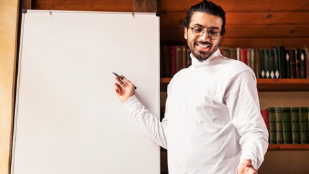 Indian Male Teacher Having Distant Class Standing Near Blackboard Indoorsの写真素材