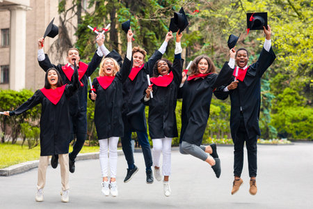 Happy students celebrating graduation from university, jumping upの写真素材