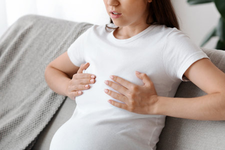 Woried pregnant woman suffering pain in breast, massaging her chest at home