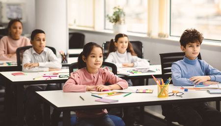 Portrait of focused diverse pupils sitting at desk in classroomの写真素材