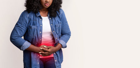 Upset african american young woman suffering from abdominal painの写真素材