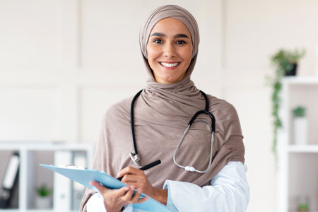 Cheerful pretty woman in hijab doctor posing in cabinetの写真素材