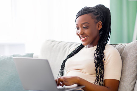 Happy black woman freelancer working from home, using modern laptopの写真素材