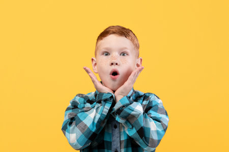 Shocked kid keeping mouth open and touching faceの写真素材