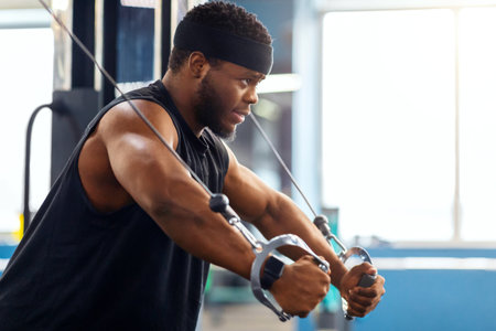 Young black sportsman training triceps on block exerciser in gym