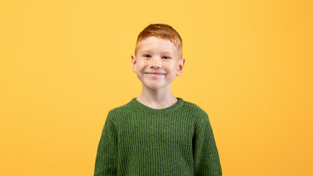 Happy cute ginger boy posing on yellow