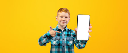 Smiling boy pointing at mobile phone with empty screenの写真素材