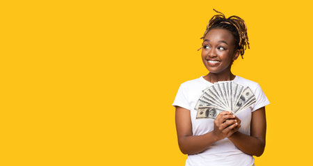 Emotional black woman holding money and looking at copy space