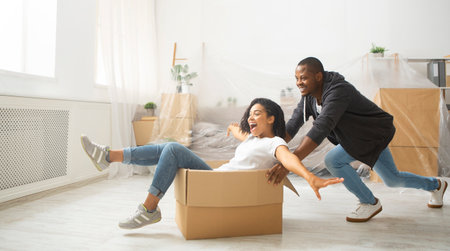 African american husband rolling his wife in cardboard box