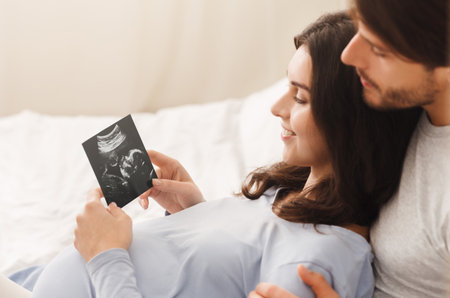 Happy pregnant woman and her husband looking at sonogram picture