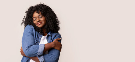 Joyful black lady in love hugging herselfの写真素材