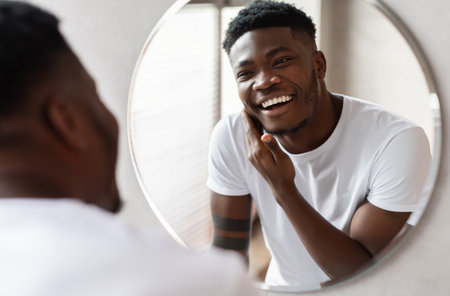 Unshaven African American Guy Touching Face With Bristle In Bathroomの写真素材