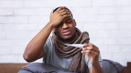 Ill African Guy Having Fever Measuring Temperature Sitting In Bedroom