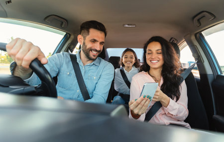 Car navigation app. Happy woman showing gps application on cellphone to driver man, family...