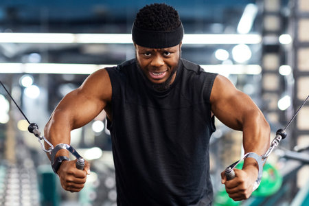 Motivated black sportsman having workout on crossover machine