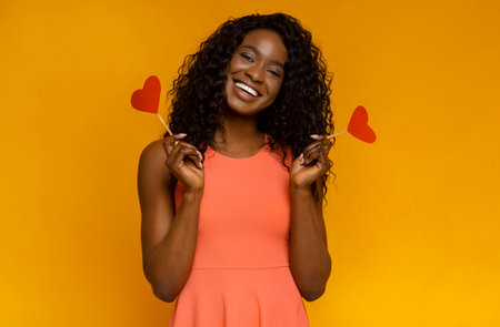 Sweet african girl with red hearts over yellow backgroundの写真素材
