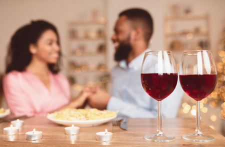 Black man having dinner with woman, focus on wine glassesの写真素材