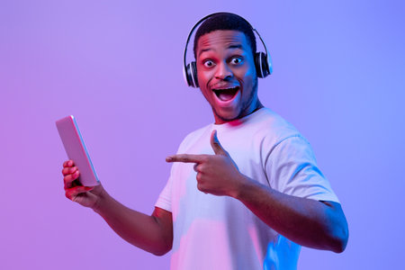 Modern Gadgets For Entertainment. Happy black man in headphones using digital tabletの写真素材