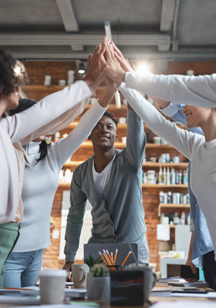 Black manager giving high five to his international young teamの写真素材