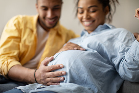 Black Spouses Expecting Baby, Husband Touching Pregnant Wifes Belly Indoorの写真素材