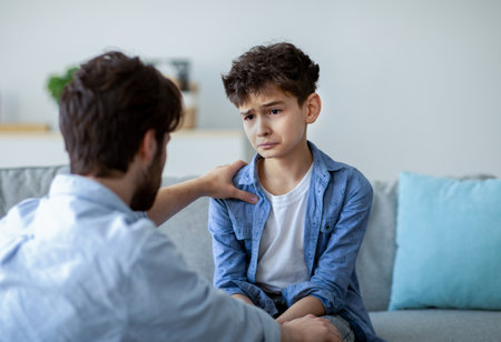 Father and sad son having heart to heart talk at home, daddy trying to solve problems, parent calming down boyの写真素材