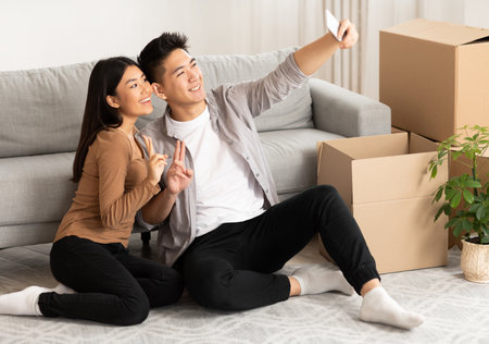 Asian man and woman taking selfie sitting on the floor