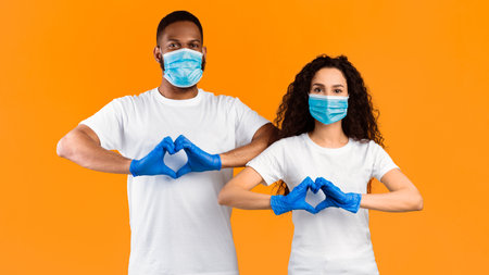 Couple Gesturing Heart Shape Wearing Masks And Gloves, Yellow Background