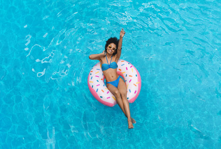 Top view of gorgeous black lady swimming on inflatable ring in pool