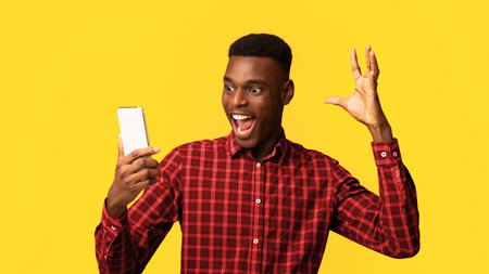 Online Win. Overjoyed African American Guy Looking At Smartphone Screen With Excitementの写真素材