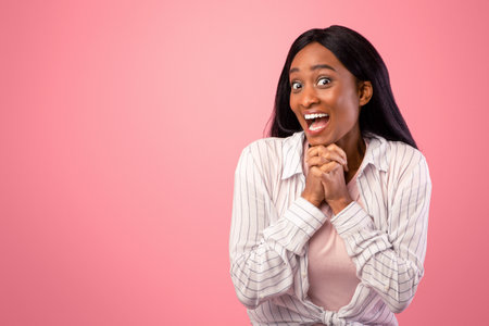 Beautiful young black woman expressing excitement or surprise on pink studio backgroundの写真素材