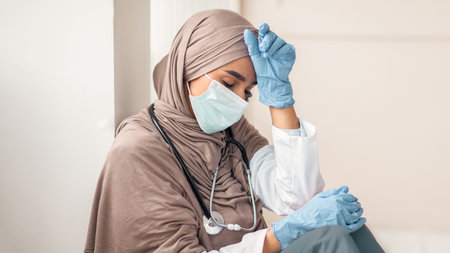 Upset woman in hijab doctor having difficult day at clinicの写真素材