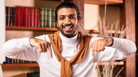 Happy Indian Teacher In Headphones Pointing At His Desk Indoorsの写真素材