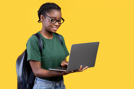 Cheerful Black Student Woman Using Laptop Over Yellow Background, Panoramaの写真素材