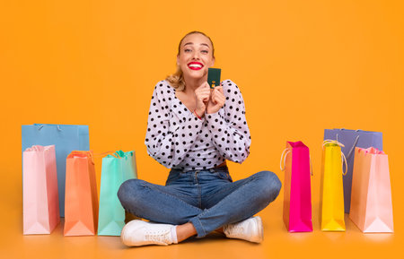 Happy woman holding credit card sitting with shopping bags
