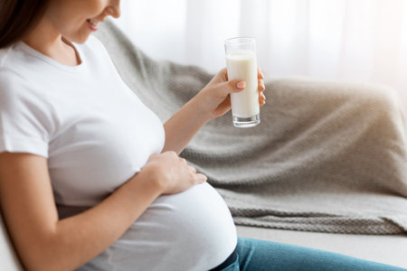 Cropped Shot Of Pregnant Woman Holding Glass With Milk And Touching Tummyの写真素材