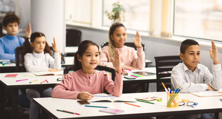 Diverse group of little schoolchildren raising hands at classroom