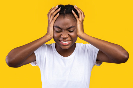 Black Lady Touching Head Suffering From Headache Pain, Yellow Backgroundの写真素材