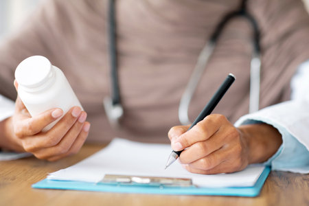 Female doctor holding medicine, writing prescription in medical chartの写真素材
