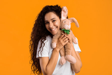 Volunteer Woman Holding Bunny Toy Smiling Standing Over Yellow Backgroundの写真素材
