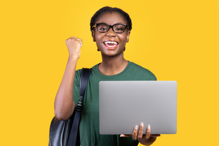 Joyful Female Student With Laptop Gesturing Yes On Yellow Background