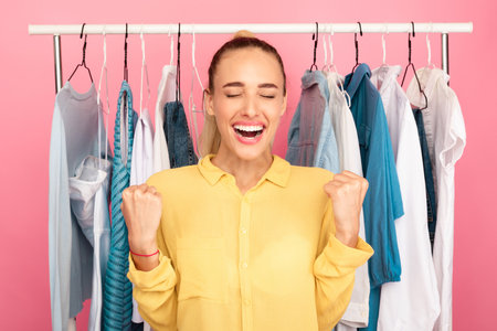 Overjoyed young woman screaming with joy choosing clothesの写真素材