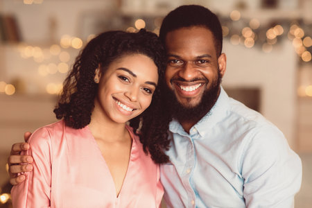 Smiling black man hugging his woman, looking at cameraの写真素材