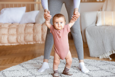 Cute baby taking first steps with mother help, home interiorの写真素材