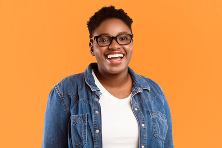 Cheerful African Plus-Size Woman Posing Over Yellow Studio Background