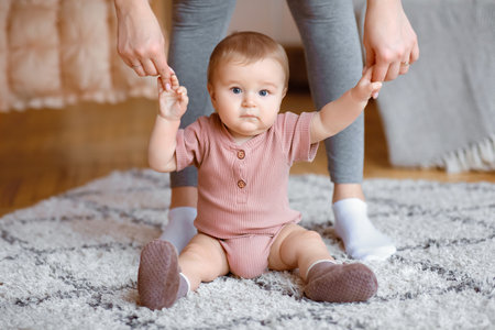 Closeup of adorable kid holding mother hands, sitting on floorの写真素材