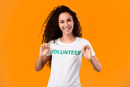 Woman showing volunteer text on her uniform t-shirt, studio shotの写真素材