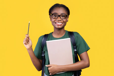 African Female Student Having Idea Pointing Pencil Up, Yellow Backgroundの写真素材