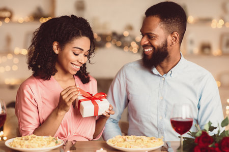 Black woman unwrapping present from her boyfriendの写真素材