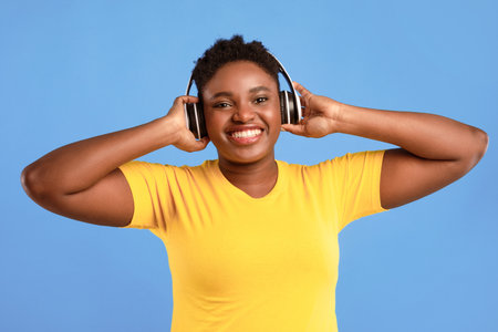 African Woman Listening Music Wearing Wireless Headphones On Blue Background